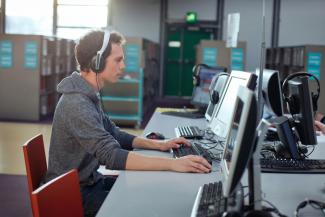 Man wearing a headset and focusing on a computer-based training.
